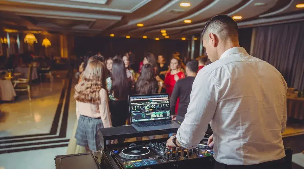 DJ at the booth looking out over guests on the dance floor
